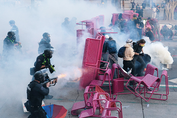 2025年6月8日,抗议者在美国加利福尼亚州洛杉矶的联邦拘留中心附近的长凳后躲避 新华社/美联 2025年6月8日,抗议者在美国加利福尼亚州洛杉矶的联邦拘留中心附近的长凳后躲避 新华社/美联